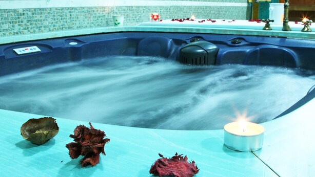 A hot tub with a candle and decorative items on a tiled surface. - Hotel Del Corso (Pula)