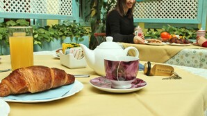 A breakfast table with a croissant, a teapot, a cup, and a glass of orange juice. - Hotel Del Corso (Pula)