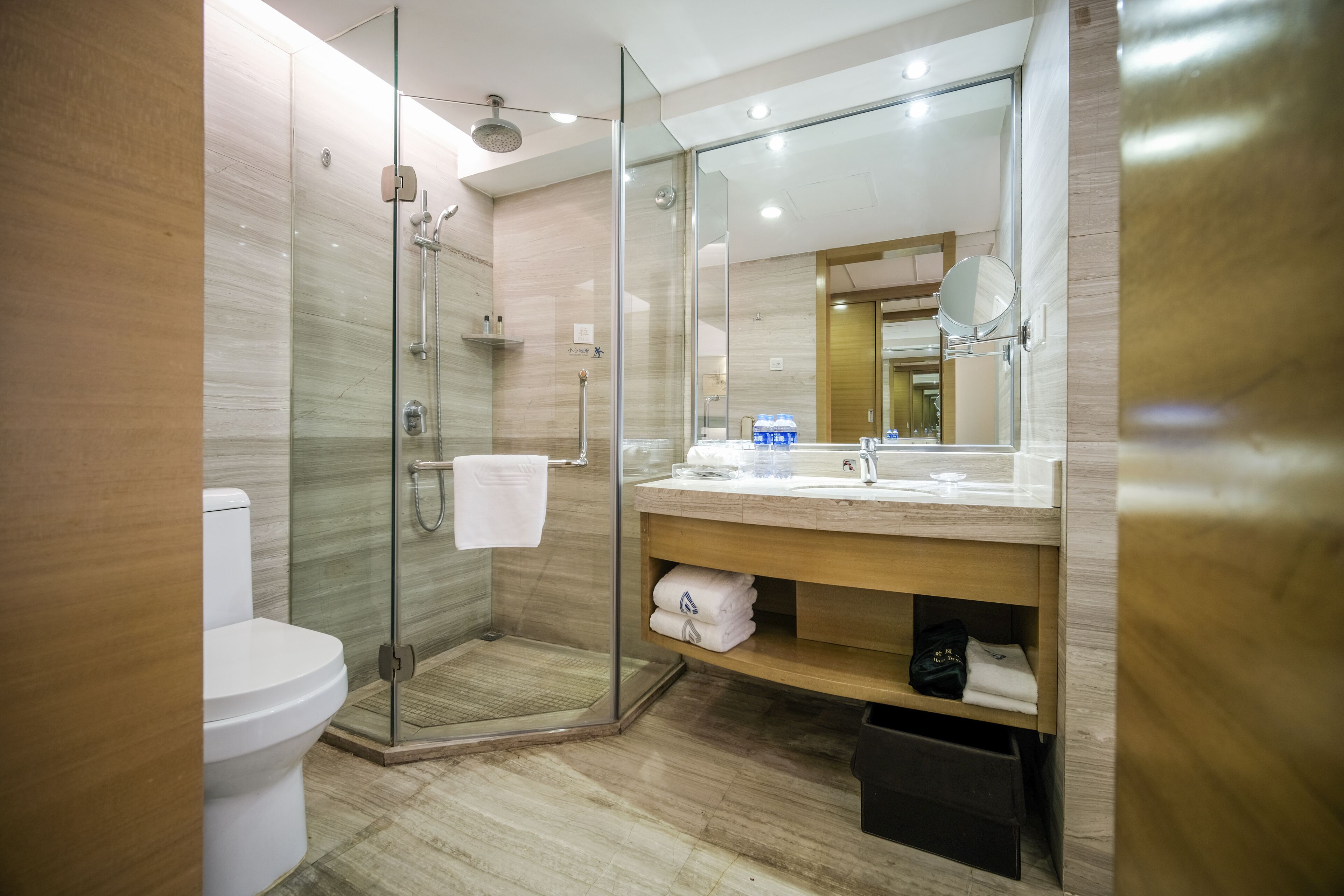 A modern bathroom with a glass-enclosed shower, a toilet, a sink with a mirror, and a towel rack.
