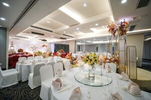 Un salón de banquetes con mesas redondas dispuestas para eventos, con manteles blancos, sillas y centros de mesa florales.