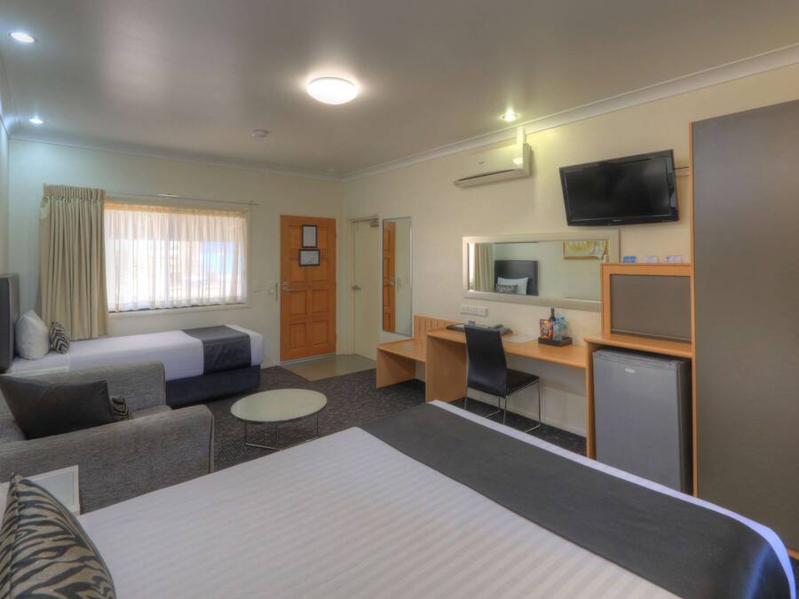 A hotel room with two beds, a desk, a chair, a TV, and a wardrobe.