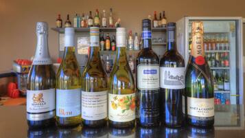 A selection of wine bottles on a bar counter with a background of various liquor bottles on shelves.