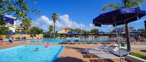 Una piscina al aire libre, sombrillas, sillones reclinables de piscina