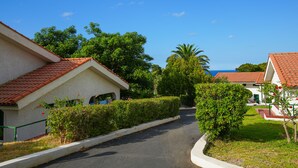 A residential street with houses featuring red-tiled roofs and white walls, surrounded by greenery and a clear blue sky. - Cefalù resort - Sporting Club (Cefalù)