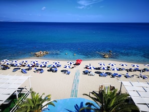 A beach with clear blue water, numerous umbrellas, and lounge chairs. - San Domenico Hotel (Soverato)