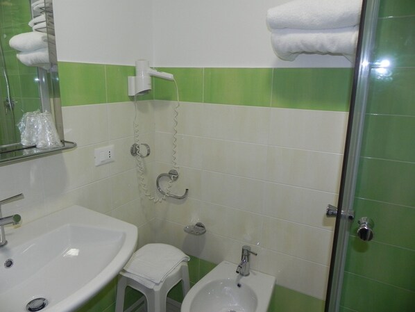 A bathroom with a sink, bidet, and glass shower enclosure. - San Domenico Hotel (Soverato)