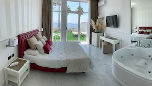 A modern hotel room with a large bed, a sitting area, a desk, a large bathtub, and a balcony with a view of the sea. - Hotel Gli Dei (Pozzuoli)