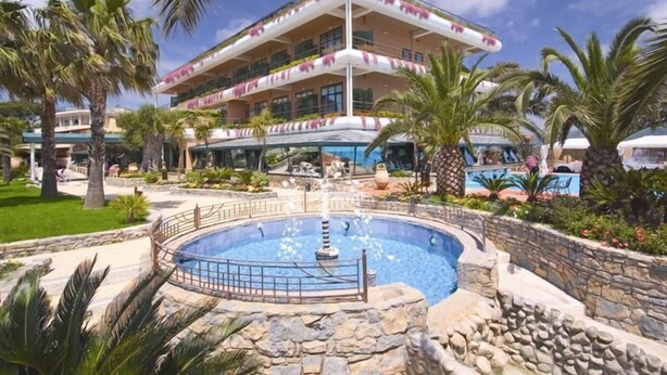 A hotel with a pool, palm trees, and a fountain. - Hotel Gli Dei (Pozzuoli)