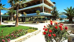 A two-story building with a balcony, surrounded by palm trees and a swimming pool. - Hotel Gli Dei (Pozzuoli)