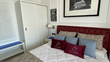 A neatly arranged bedroom with a bed, a wardrobe, a nightstand, and a framed picture on the wall.