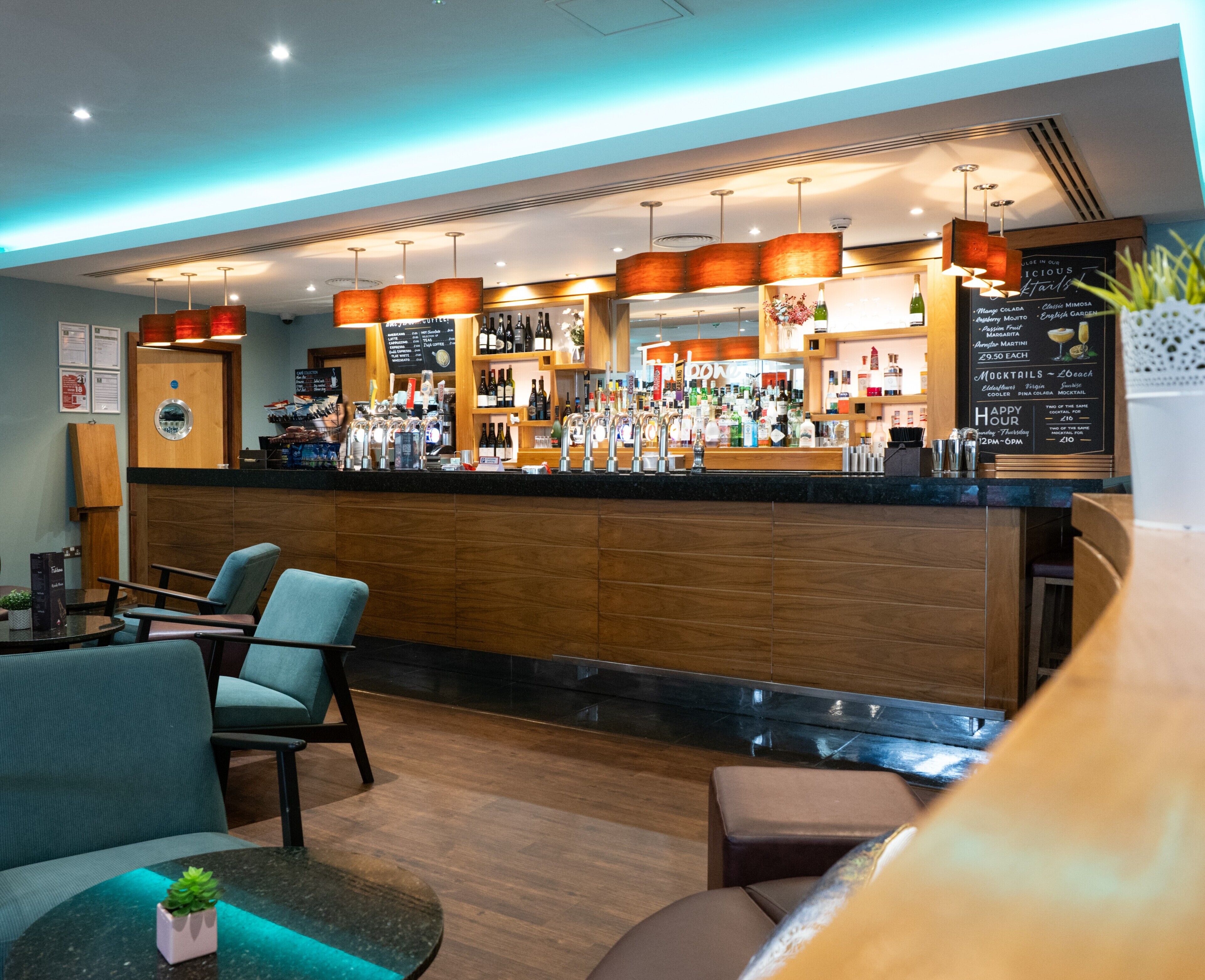 A bar area with a wooden counter, seating, and a menu board.