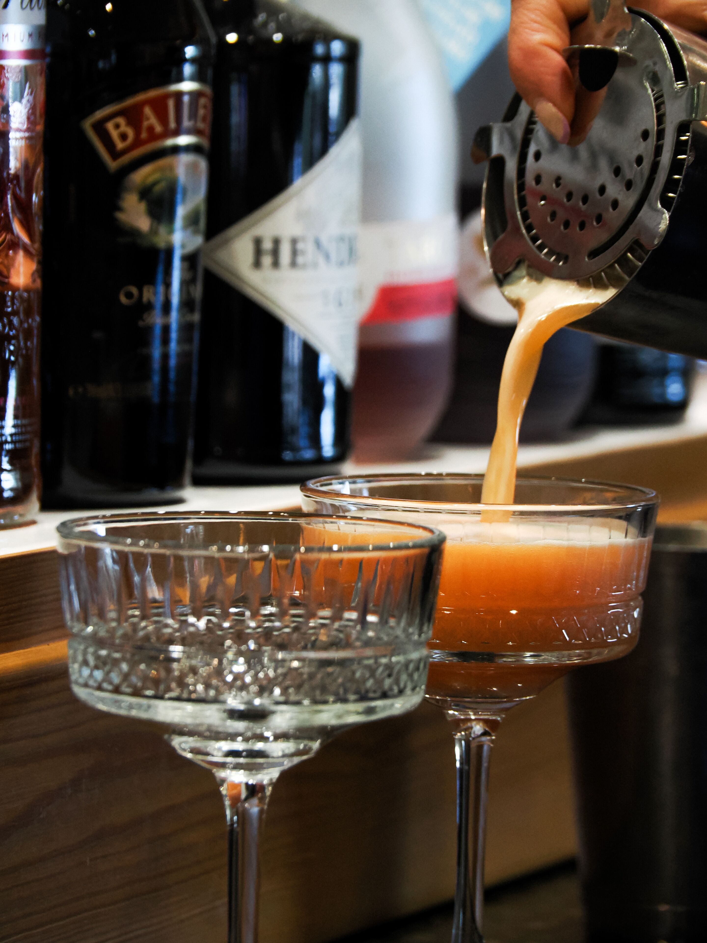 A bartender pouring a drink into a glass.