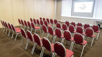 A conference room with rows of red chairs, a projector screen, and a large window.