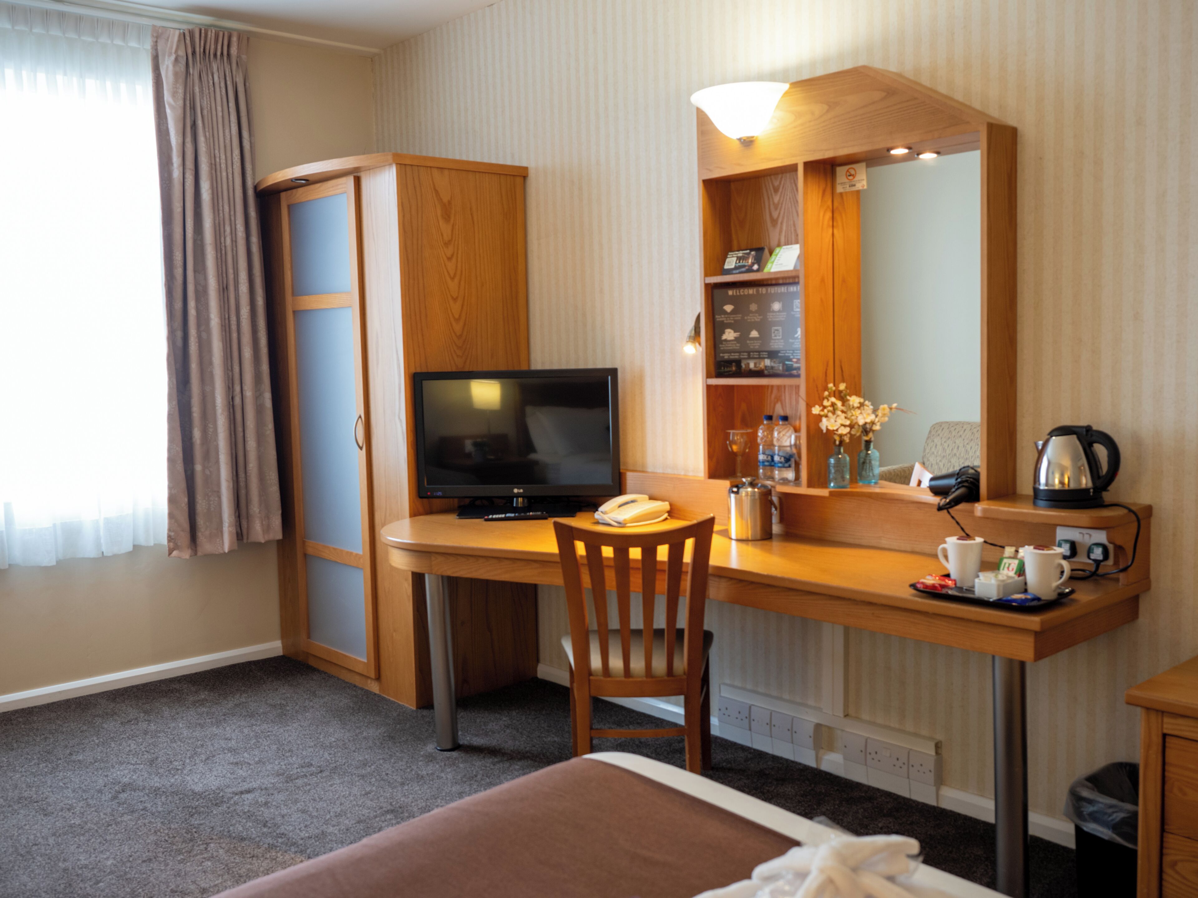 Habitación de hotel con escritorio, silla, televisión y cama.
