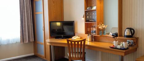 Habitación de hotel con escritorio, silla, televisión y cama.