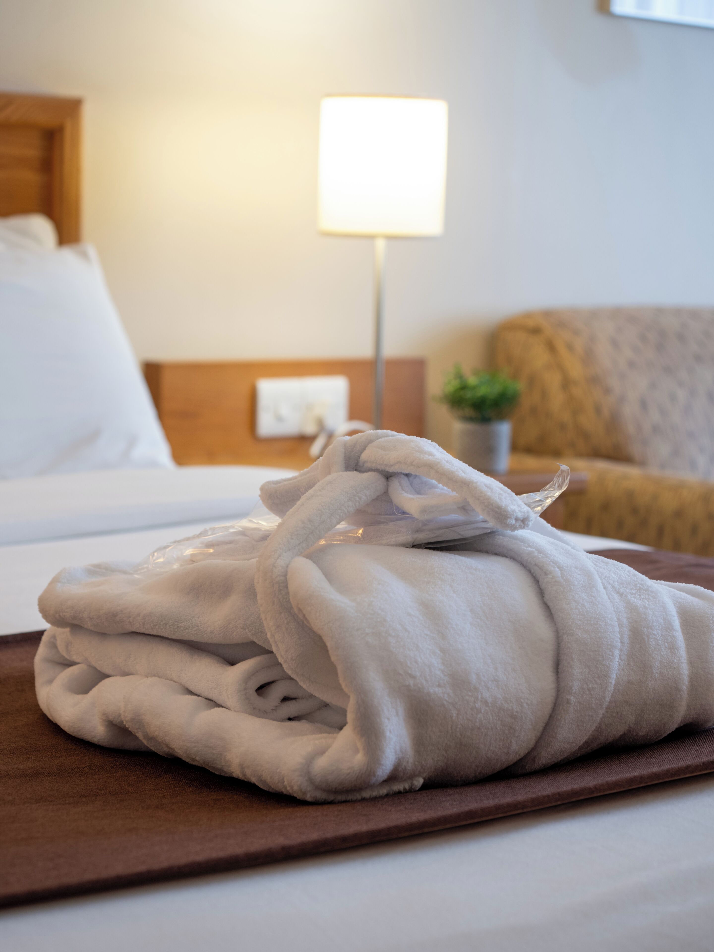 A neatly folded white bathrobe on a tray in a hotel room.