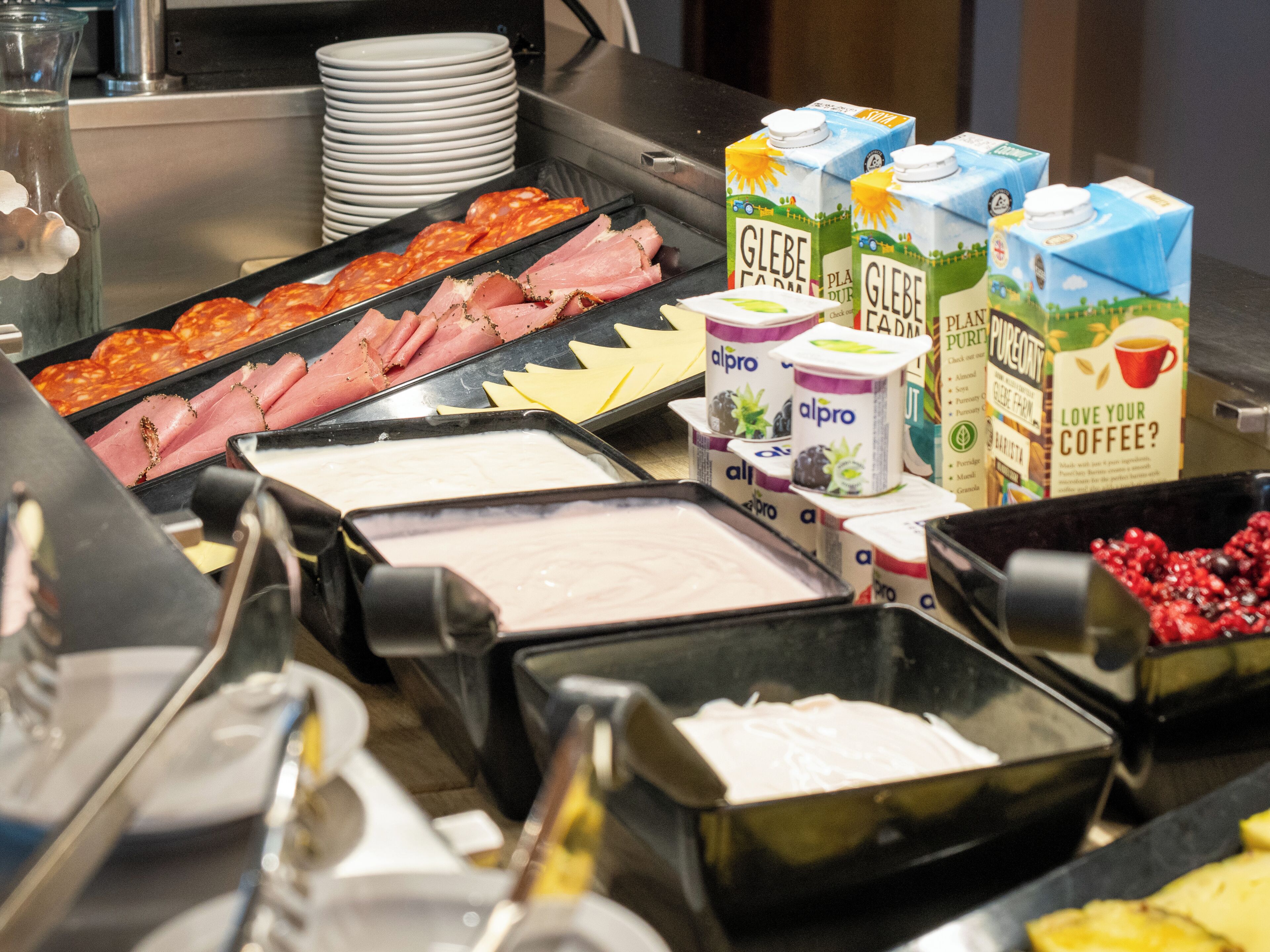 A buffet with various food items including meats, cheeses, and dairy products.