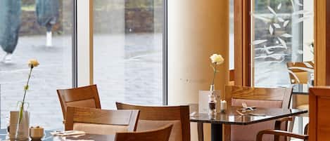 Un restaurante con mobiliario de madera y ventanas amplias.