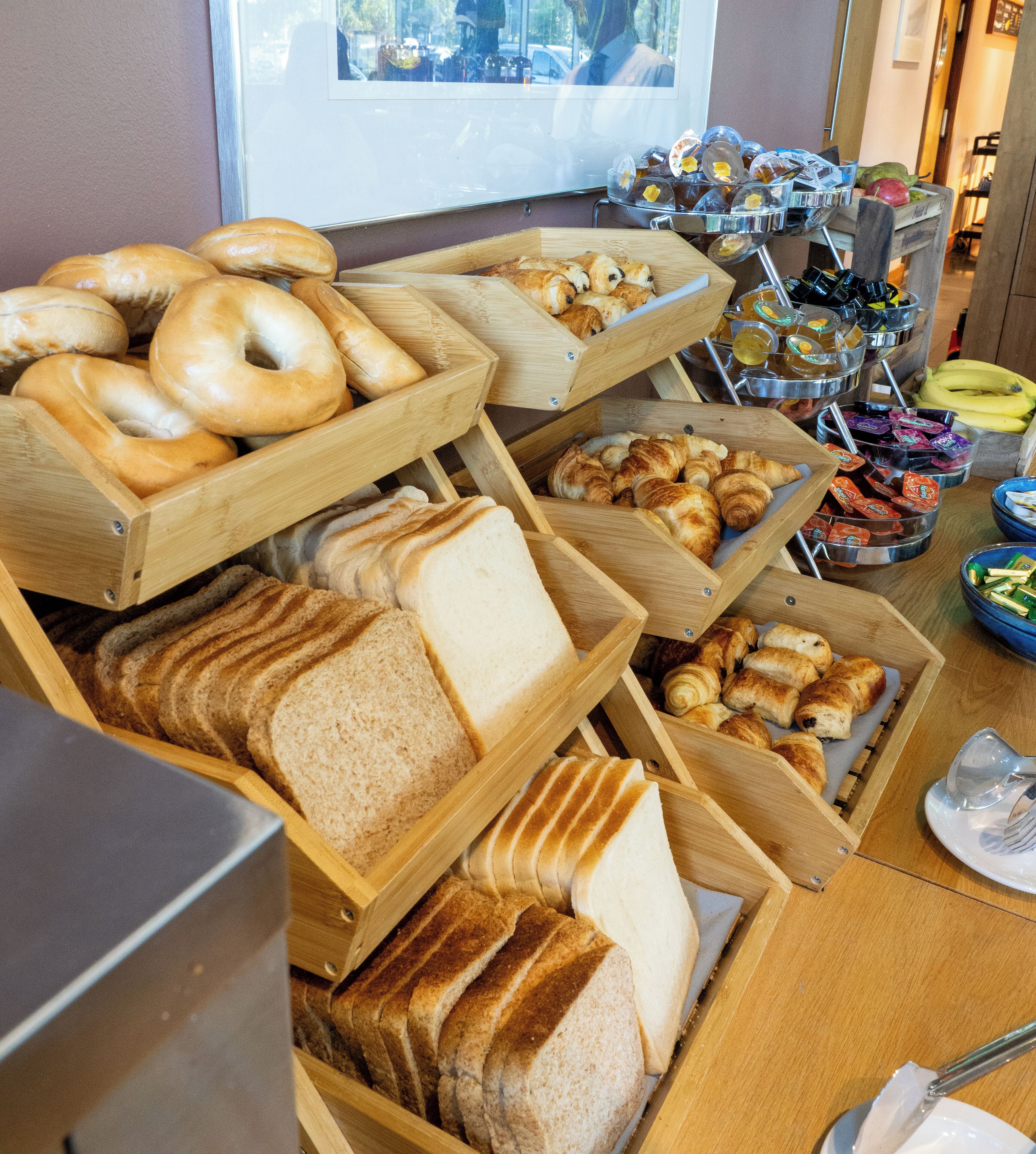 A breakfast buffet with various breads, pastries, and fruits.