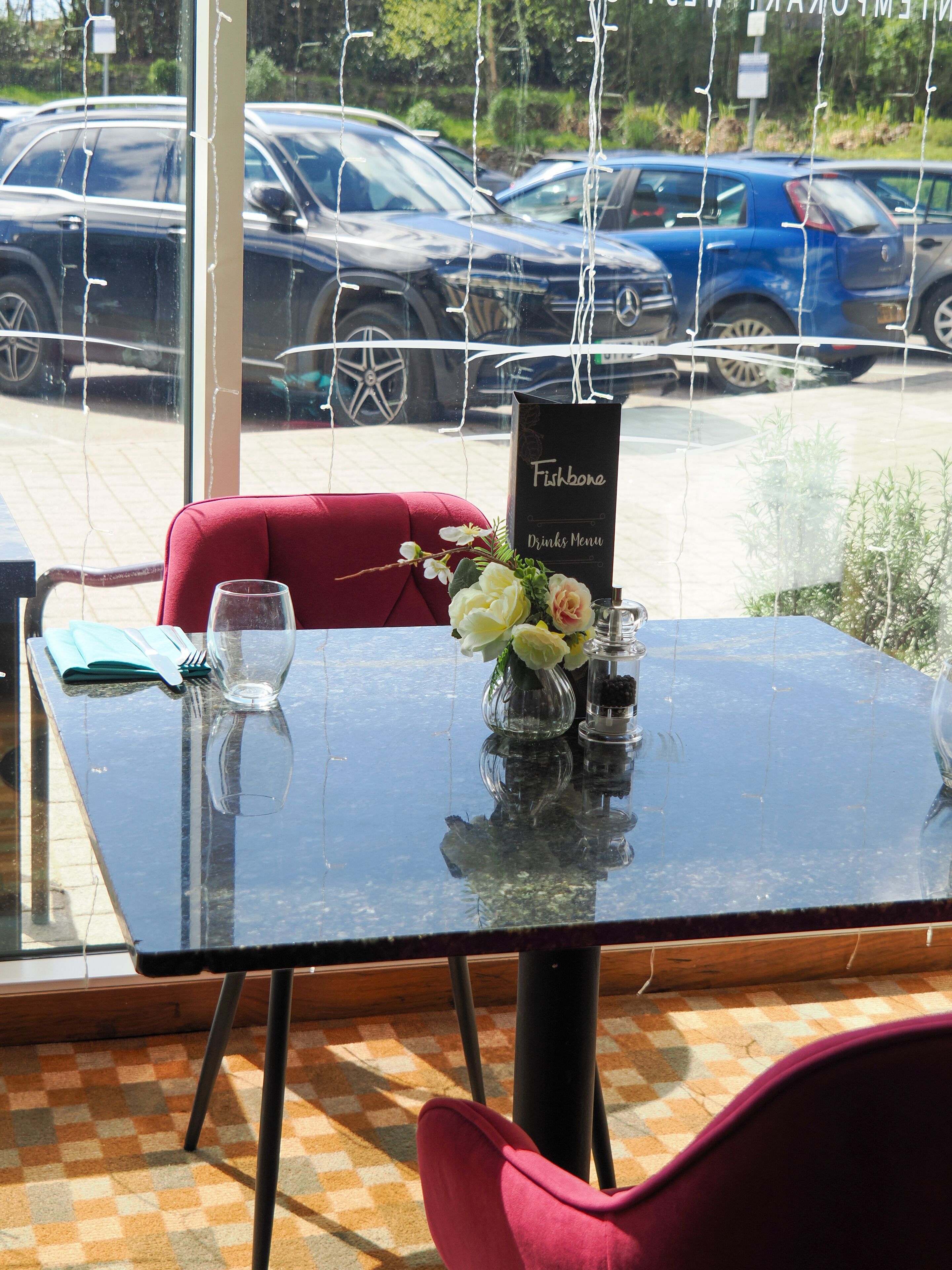 A table with a menu, a vase with flowers, and a glass.