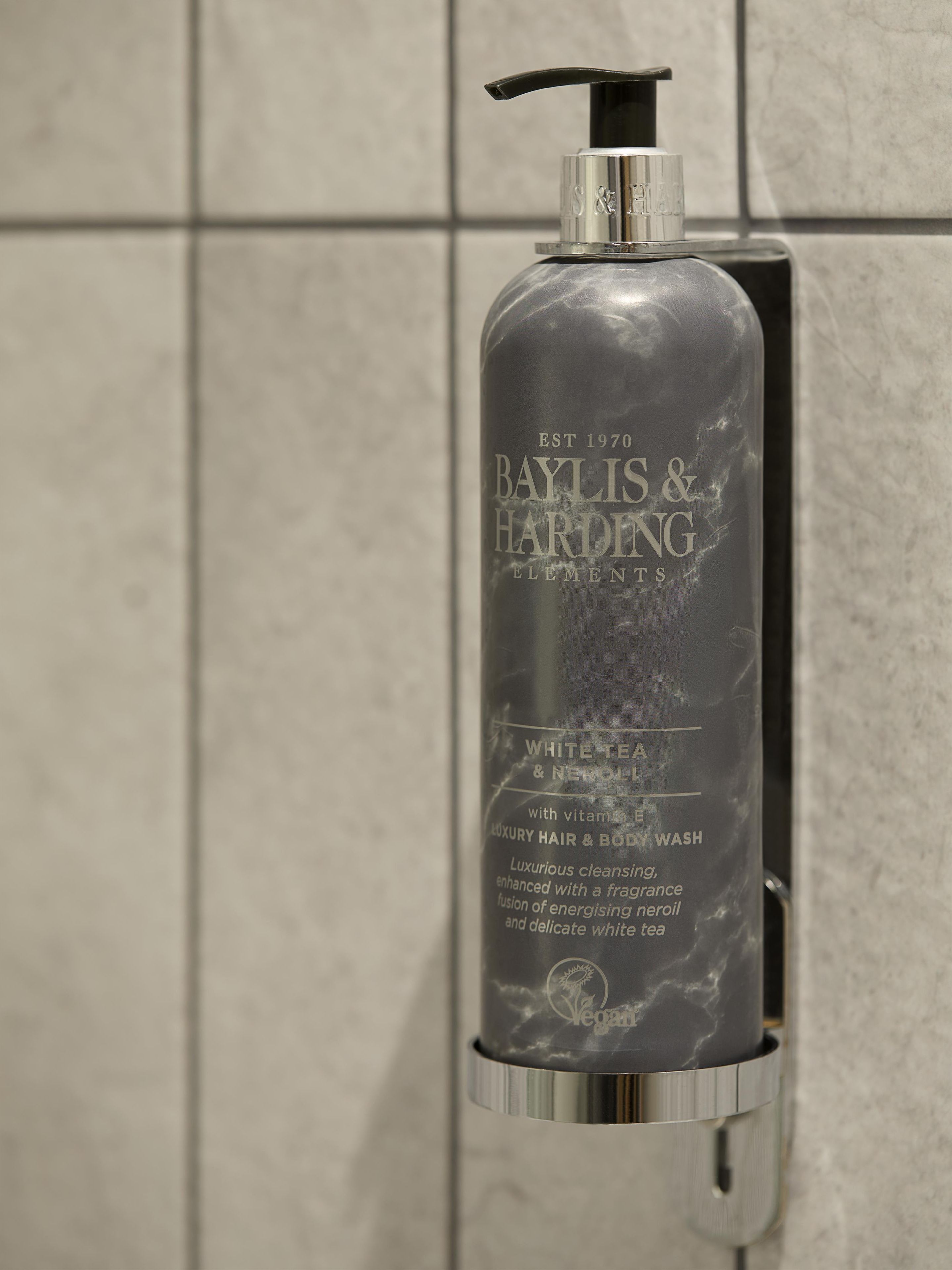 Eine Flasche von Baylis & Harding Elements mit Pumpspender, auf einer gefliesten Wand platziert.