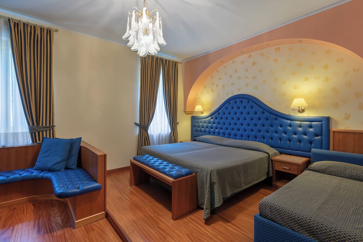 A bedroom with a large bed, a bench, and a small table.