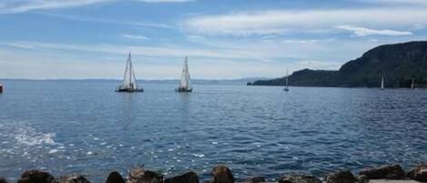 A coastal scene with a rocky shoreline and sailboats on the water.