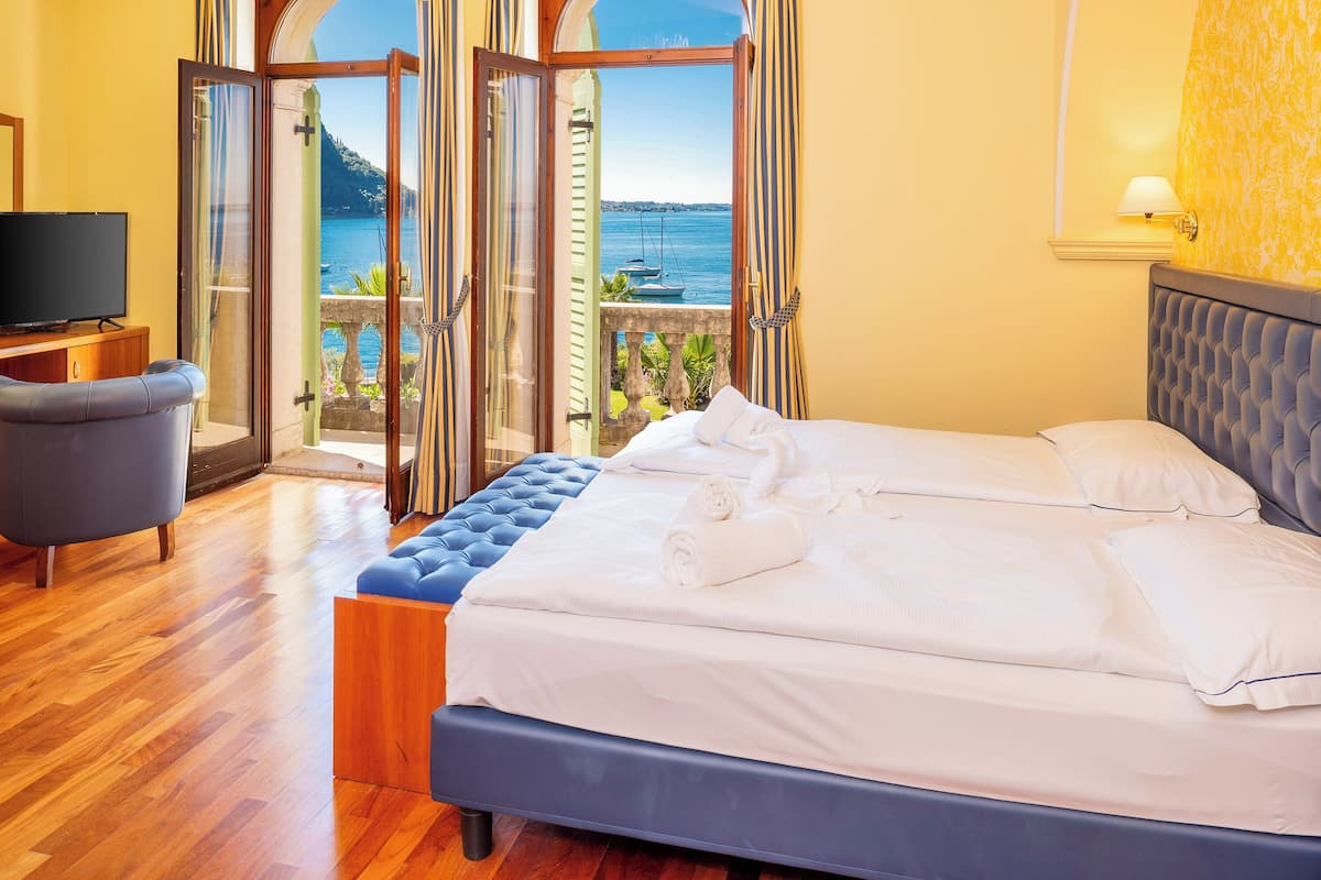 A hotel room with a bed, a TV, and a view of the sea.