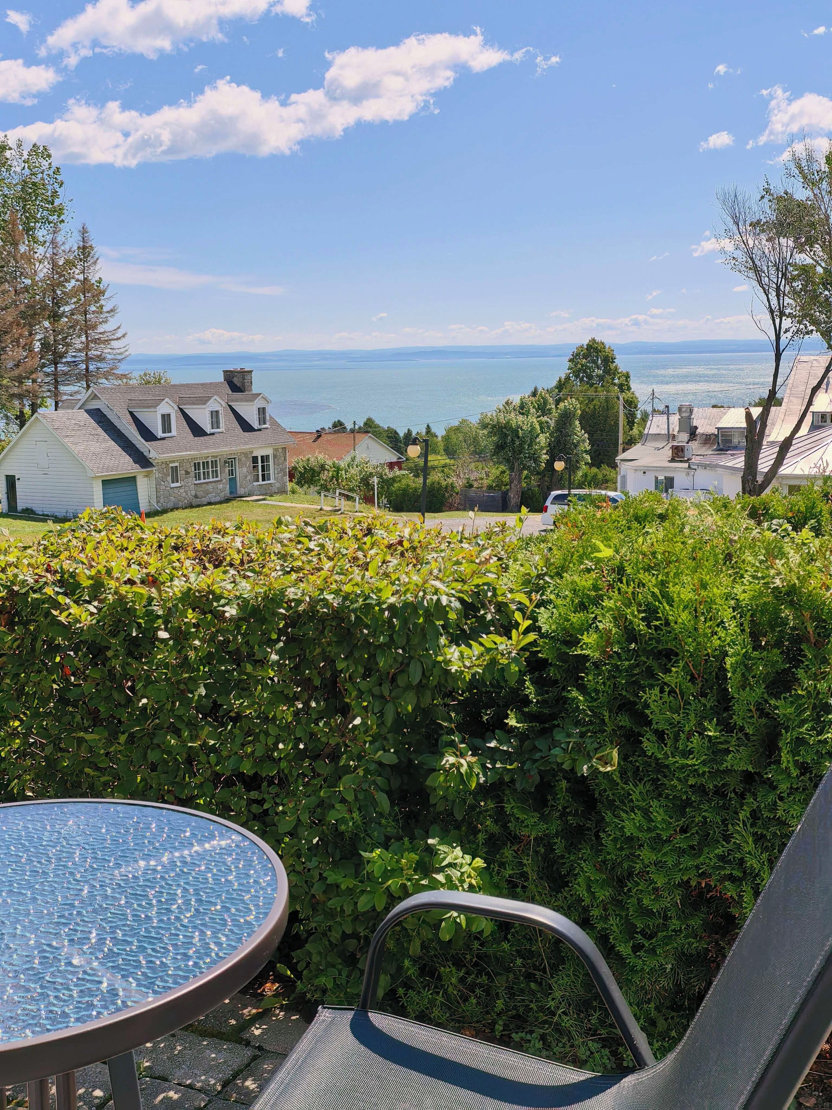Eine Terrasse mit Tisch und Stühlen, mit Blick auf ein Wohngebiet mit Häusern und Wasser.