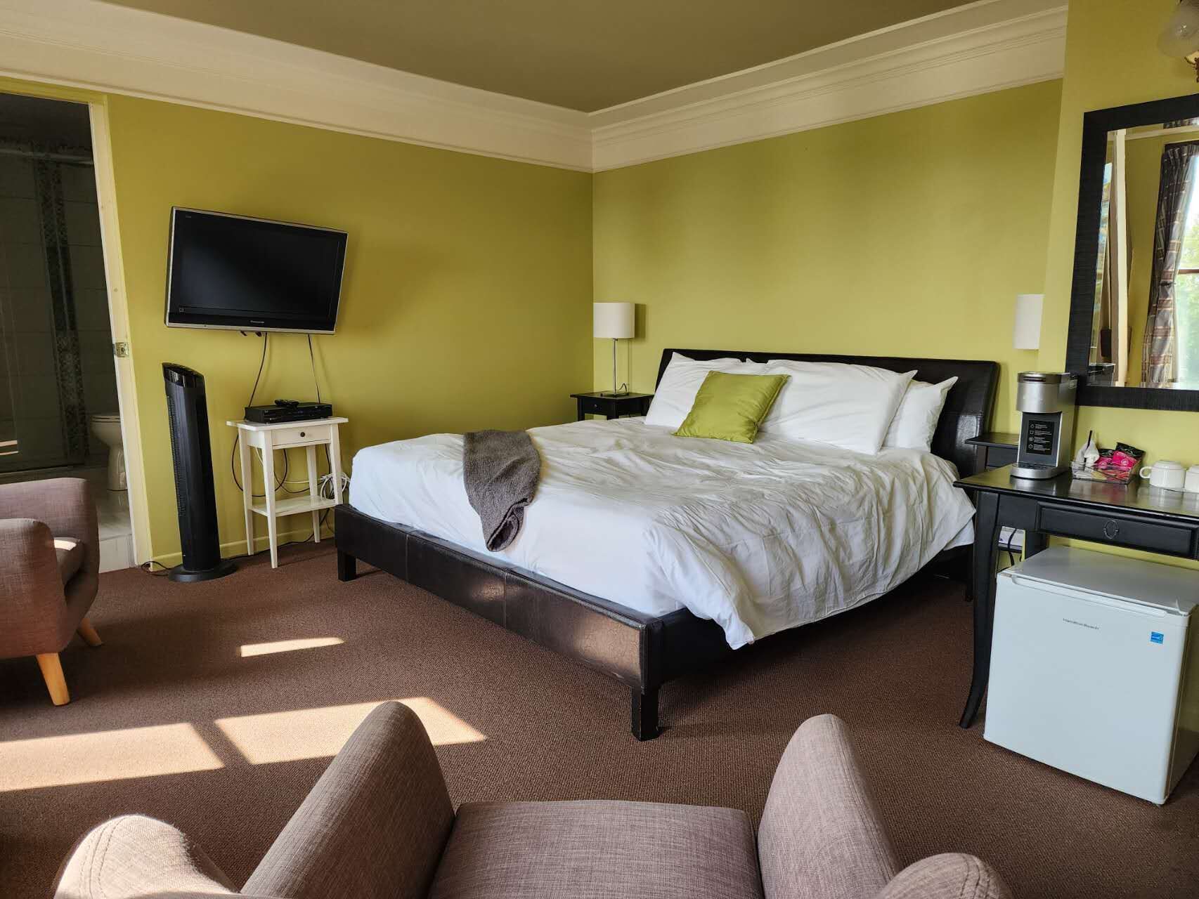 Ein Hotelzimmer mit Bett, Fernseher, Kaffeemaschine und Schreibtisch.