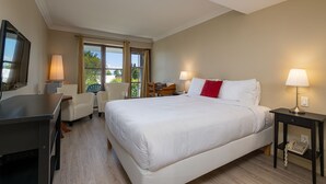 A hotel room with a large bed, two bedside tables with lamps, a desk with a chair, and a TV. - Auberge des Nuages (La Malbaie)