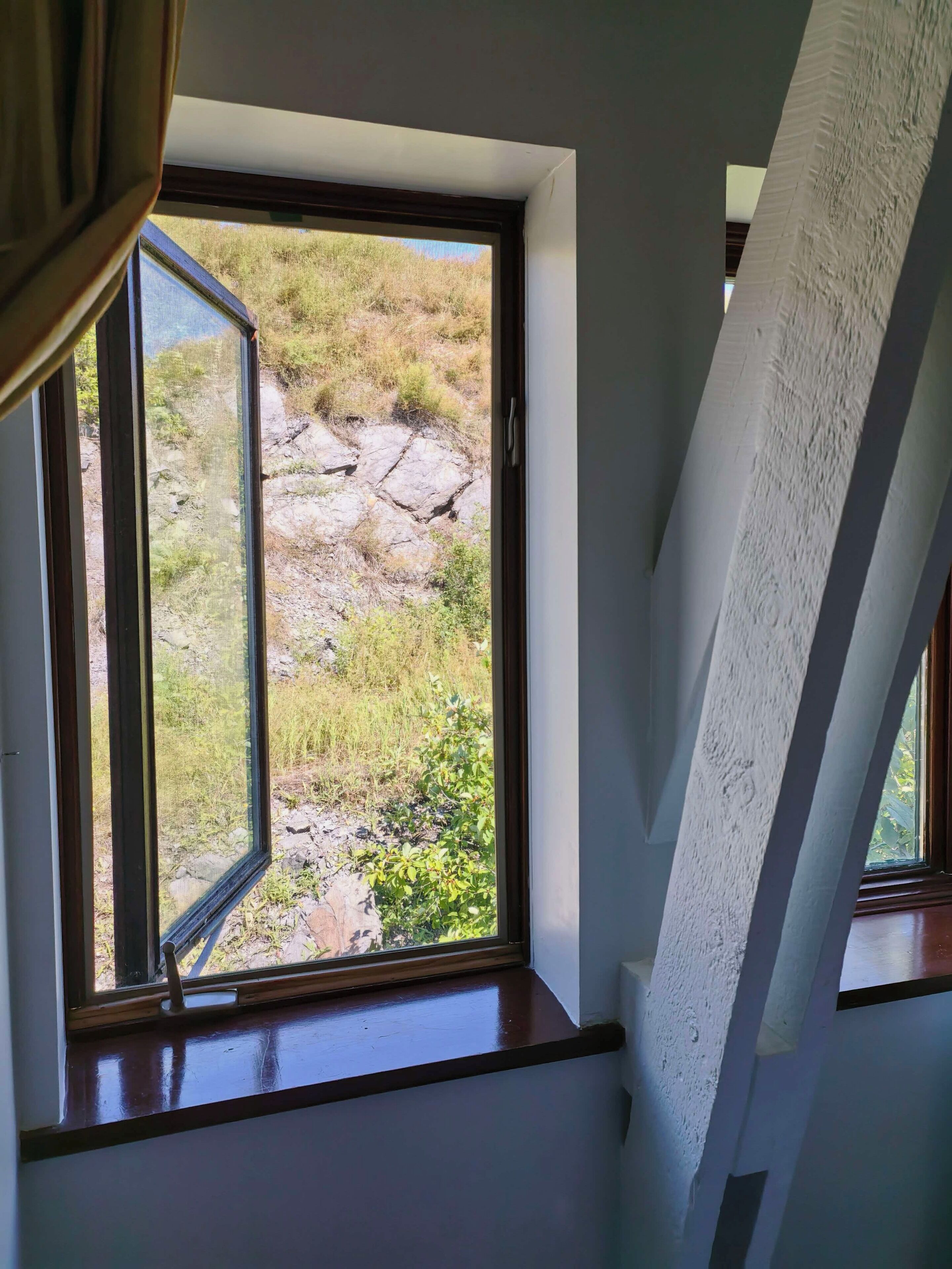 A room with a large window overlooking a rocky outdoor area.