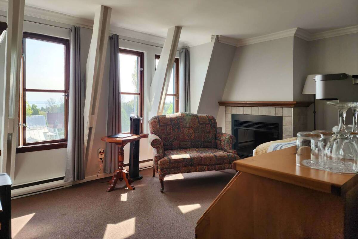 Une pièce avec un fauteuil à motifs, une cheminée et une table avec des verres.
