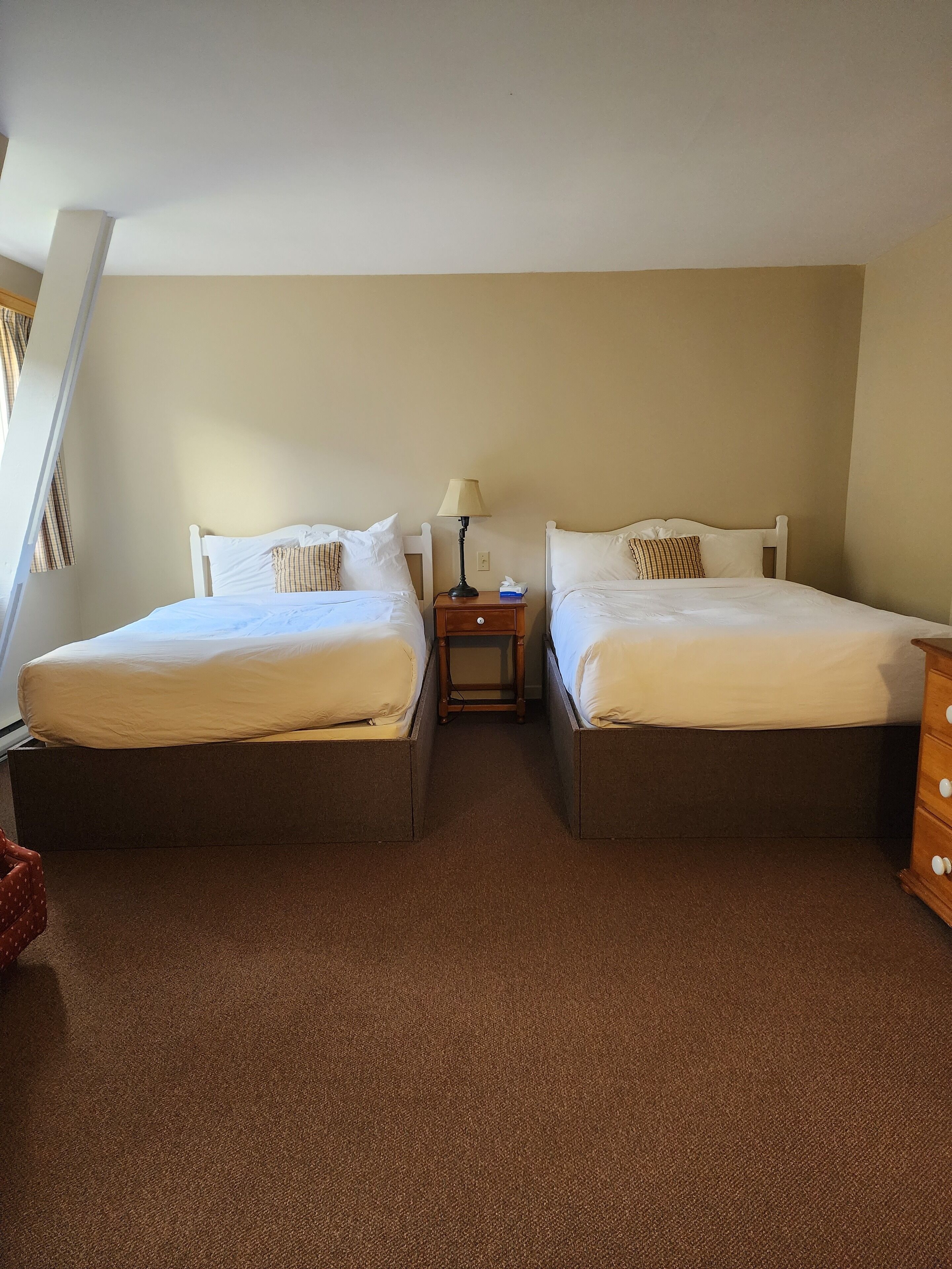A twin room with two beds, a nightstand, and a dresser.
