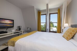 A hotel room with a bed, a desk with a computer, a television, and a window with curtains. - Auberge des Nuages (La Malbaie)