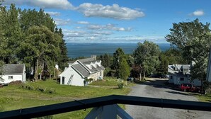 A coastal residential area with houses, a clear sky, and a view of the ocean. - Auberge des Nuages (La Malbaie)