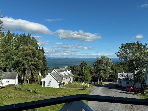A coastal residential area with houses, a clear sky, and a view of the ocean. - Auberge des Nuages (La Malbaie)