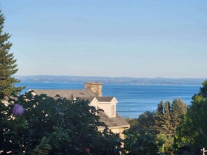 A coastal view with a building in the foreground and a clear blue sea in the background. - Auberge des Nuages (La Malbaie)