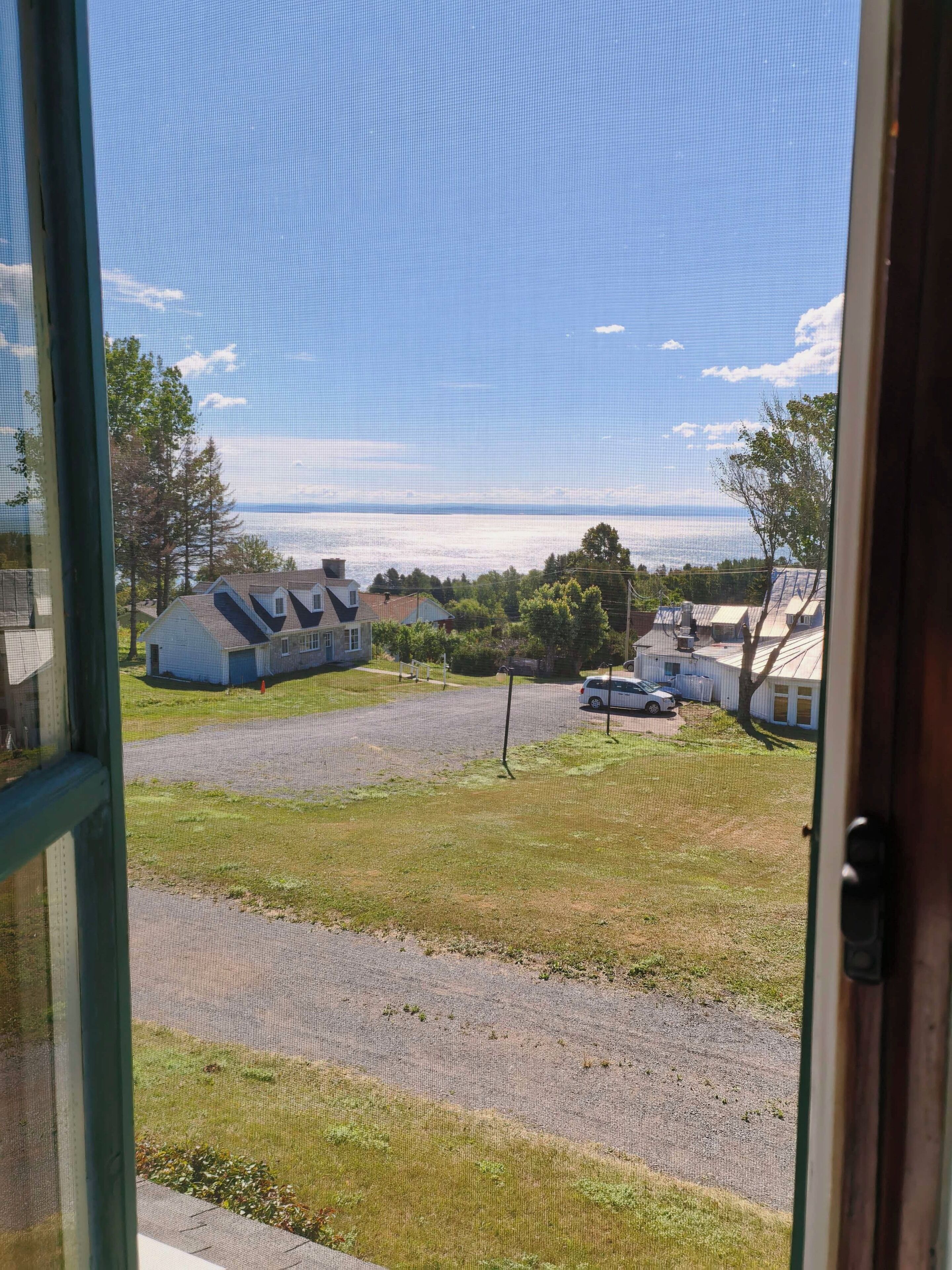 A view through a window of a residential area with houses, a parking lot, and a clear sky.