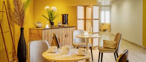 Una habitación de hotel con un mueble de madera, un juego de té y una planta decorativa.