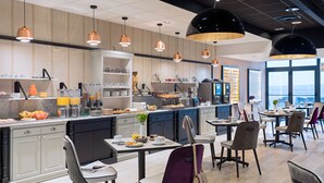 A modern kitchen with a breakfast bar, dining area with chairs, and a view of the city. - Valdys Thalasso & Spa Hotel - l’Escale marine (Douarnenez)
