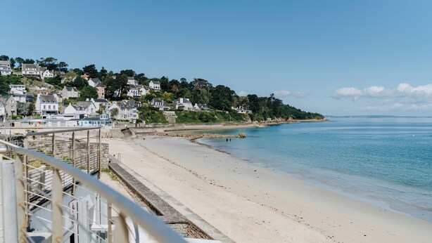 A coastal town with a sandy beach, houses on a hillside, and a clear blue sky. - Valdys Thalasso & Spa Hotel - l’Escale marine (Douarnenez)