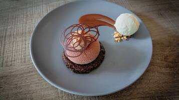Een dessert op een bord met een chocoladebasis, een bolletje ijs en een karamel drizzle.