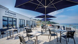 An outdoor dining area with tables and chairs, large umbrellas, and a view of the sea. - Valdys Thalasso & Spa Hotel - l’Escale marine (Douarnenez)