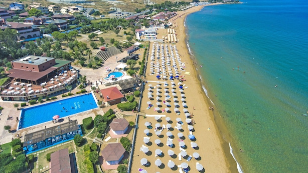 An aerial view of a coastal resort with a long sandy beach, a swimming pool, and multiple beach umbrellas. -  Fruit Village Crotone Casarossa (Crotone)