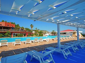 A poolside area with lounge chairs and a covered section. -  Fruit Village Crotone Casarossa (Crotone)