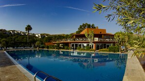 A swimming pool with a metal ladder, surrounded by a brick deck. -  Fruit Village Crotone Casarossa (Crotone)