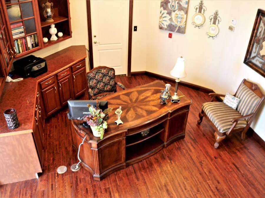 A room with a wooden desk, a chair, a lamp, and a bookshelf.