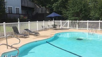 Una piscina al aire libre, sillones reclinables de piscina