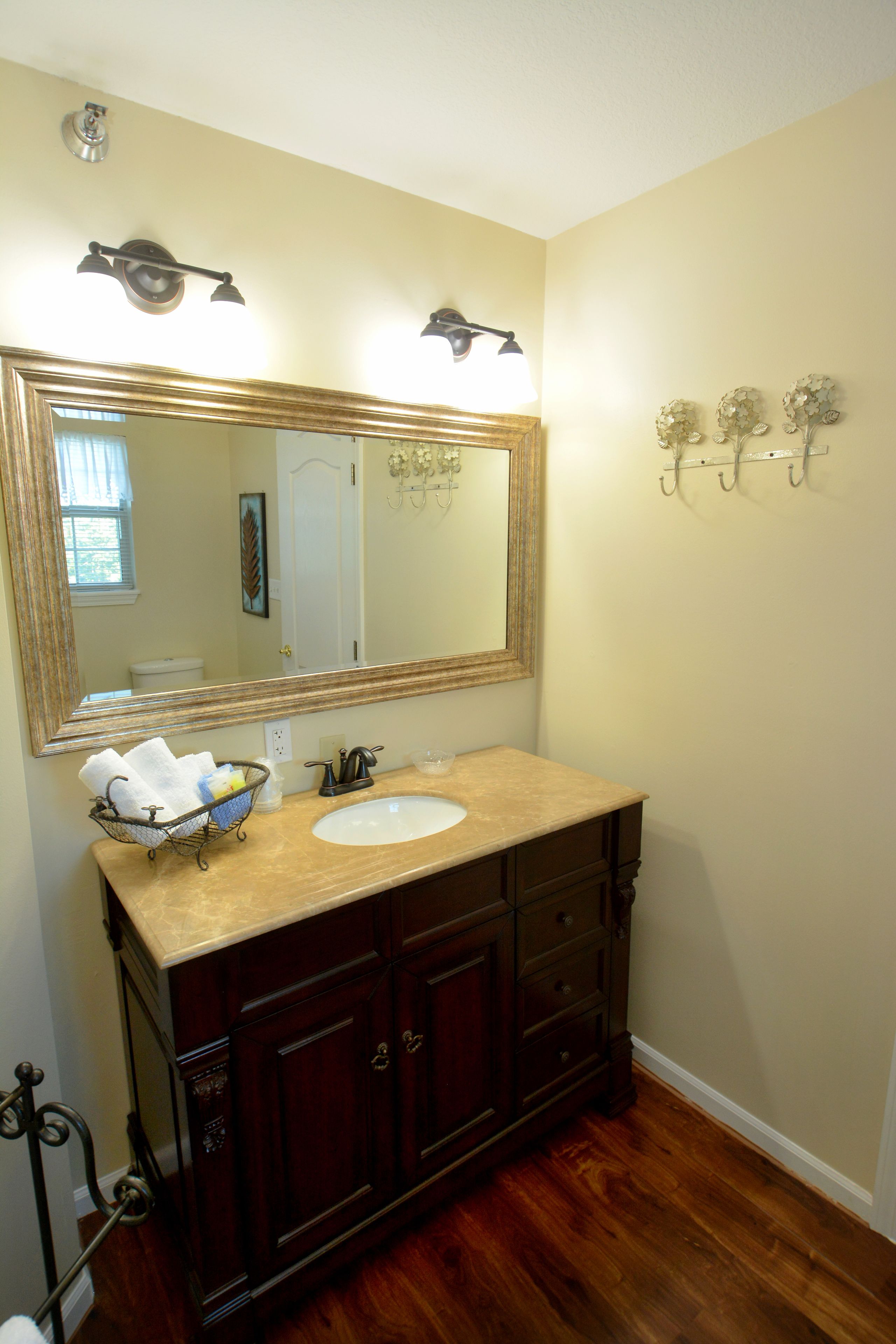 Un baño con un espejo grande, tocador de madera y lavabo.